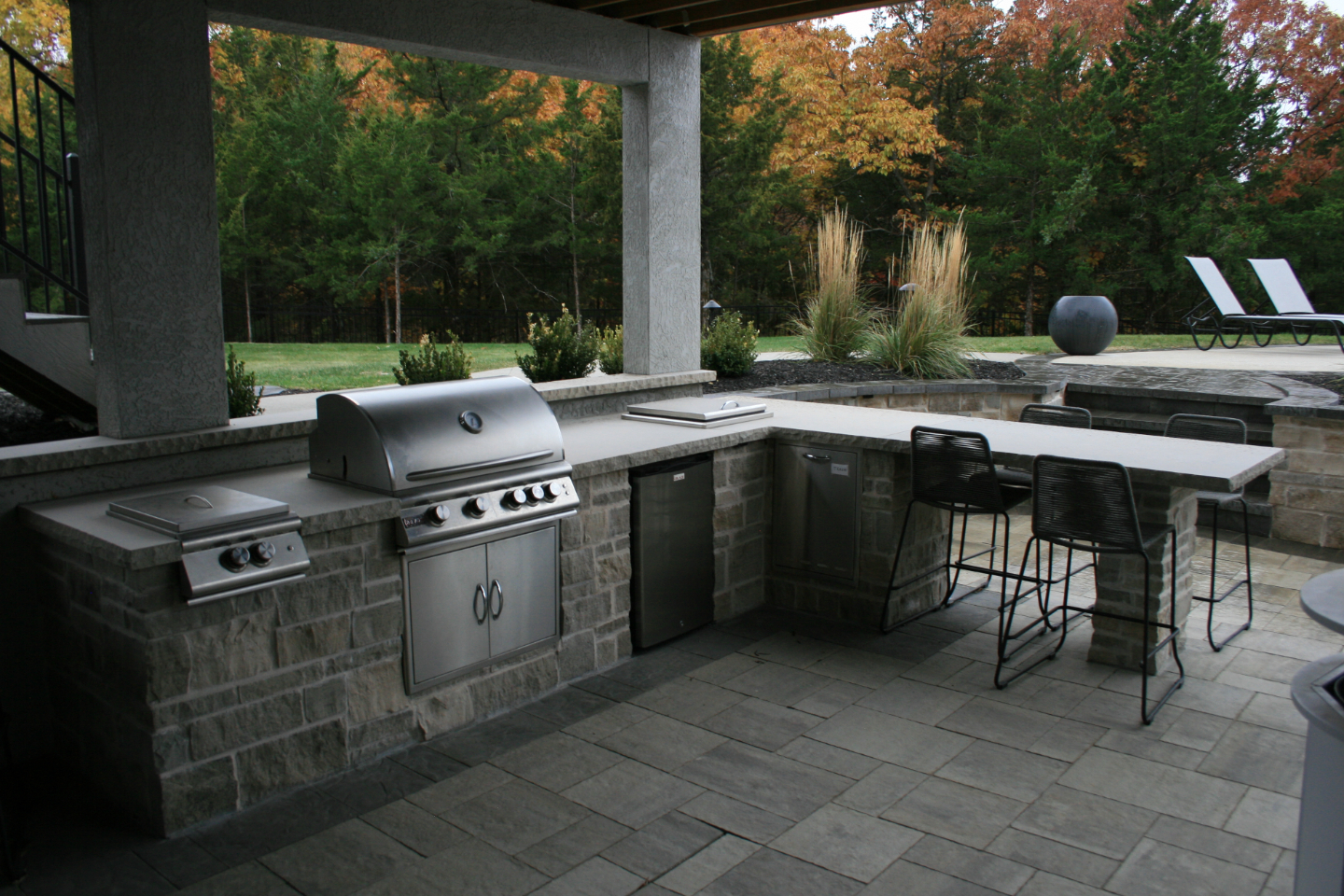 Outdoor eating area with grill and fridge built into the stone deck.