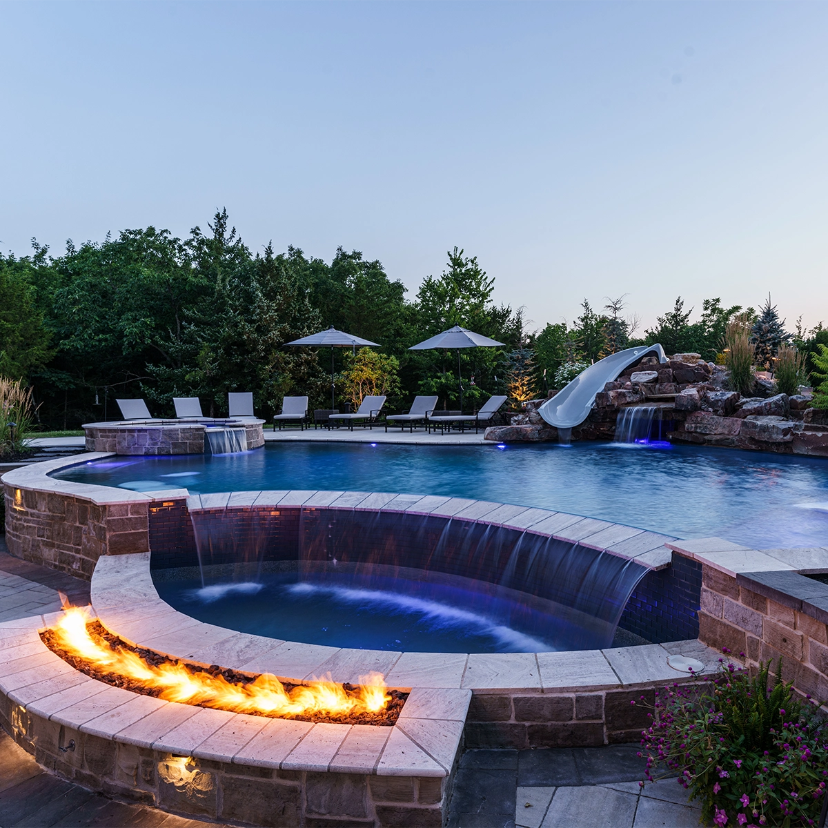 Outdoor pool with jacuzzi, waterfall, firepit and slide